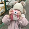 Момиче със зимни дрехи разглежда розов модел с форма на коте